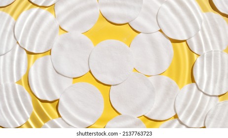 Water Drop Making Water Rings On Water Surface Over Cotton Pads On Yellow Background | Beauty Background, Make-up Remover Commercial Concept