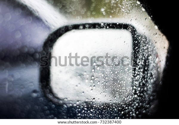 Water drop on car glass and left wing mirror,\
selective focus.Drops of rain on the car window and wing mirror in\
rainy season.Sad feeling\
concept