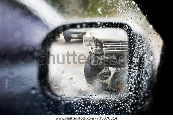 Water
drop on car glass and left wing mirror that reflect  the car get
damaged by accident on the road, selective focus. Car crash
accident on street in rainy day.Careless
concept