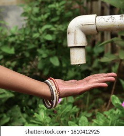 Water drop pours from the old crane into the hands. The concept of water scarcity.