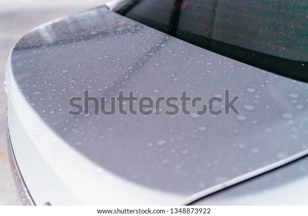 Water droplet on the car hood. Water beading\
after rain or car wash on white shiny paint surface. Beading\
created by ceramic coat or paint sealant with high surface tension.\
Water drop Backgroud.