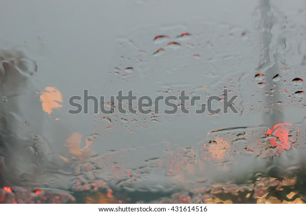 water droplets concept : Abstract of water\
droplets on car mirror in raining day with red bokeh of car light :\
abstract and background\
concept