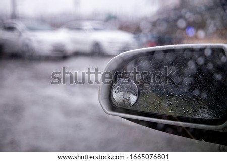 Water droplets on a car rearview mirror on a rainy day
