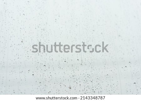 Water droplets on the glass on a rainy day. rain drops during raining in rainy day outside window glass with blurred background.