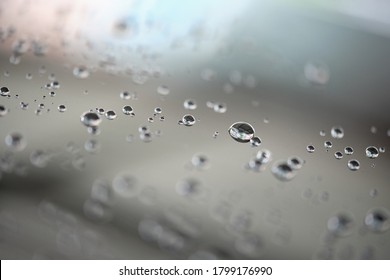 Water droplets on surface of car glass window. Car wash concept. Natural patterns of droplets on windshield. Rain drops wallpaper. Wet windscreen shot during car wash. Selective focus 