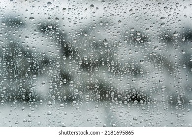 Water Droplets On A Window Pane With A Snowy Winter Garden In The Background