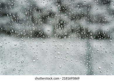 Water Droplets On A Window Pane With A Snowy Winter Garden In The Background