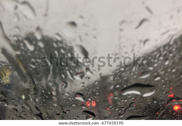 water\
droplets over front mirror of a car in heavy\
rain