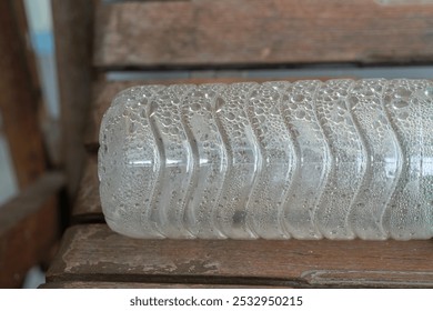 Water droplets in a plastic bottle placed on a wooden bench - Powered by Shutterstock