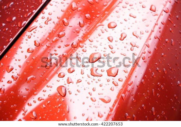 Water drops collect on top of metal red car\
surface , rain droplets