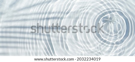 Water drops fall on the transparent surface of the water and the shadow of a palm leaf. Top view, flat lay. Banner.
