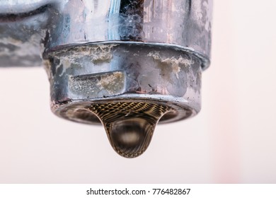 Water drops falling from dirty water tap, macro shot