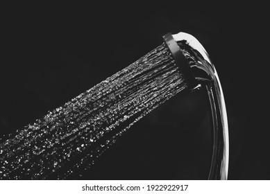 Wassertropfen, die aus Duschkopf im Badezimmer auf schwarzem Hintergrund strömen, Stoppbewegung 