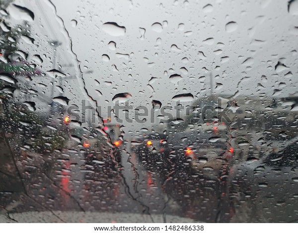 water drops in front of car mirror with blur traffic\
on road in raining day