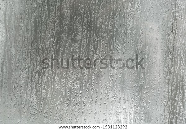 Water drops from home condensation\
on a window. grunge water drop of rain on mirror background\
