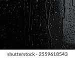 Water drops on black glass surface, closeup