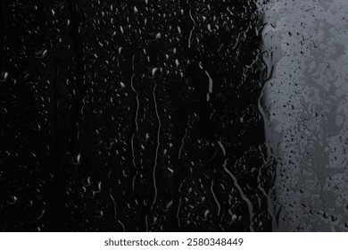 Gotas de agua en la superficie de vidrio negro, en primer plano