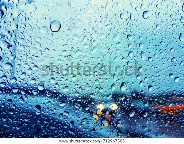 Water drops on a car glass window while driving\
in rainy weather