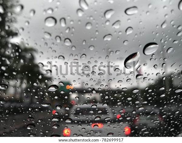 Water drops on the car glass. Water drops on the\
glass and traffic jams.Blur background and texture traffic on the\
road.