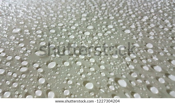 Water drops on a car roof when driving through\
the rain.\
