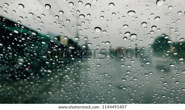 Water drops on car window after the rain with\
blur street Road and fog\
background