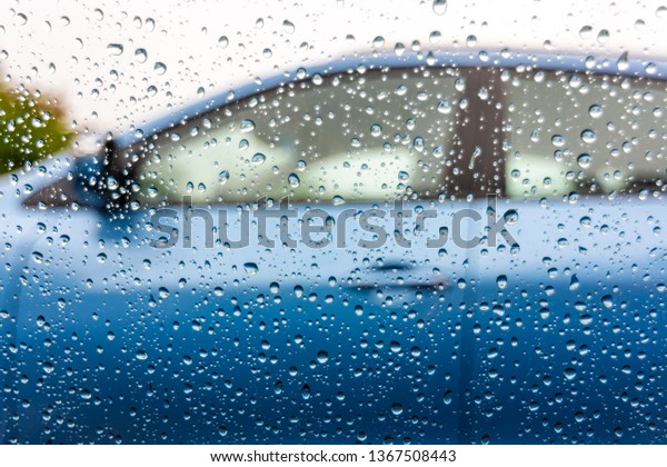 Water drops on\
the car window. View from car with raindrops on the window to next\
car with blue color. Rainy\
day.