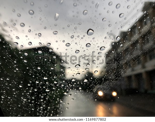 Water drops on car windshield, at\
evening, on rainstorm day, dark and blur\
background.