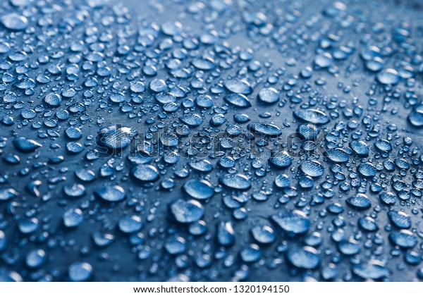 Water drops on the fabric. Rain Water droplets on\
blue fiber waterproof fabric. Water drops pattern over a waterproof\
cloth. Blue background. Dark blue rainproof tent sheet with morning\
rain drops.