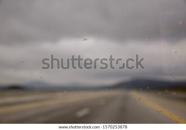 water drops on glass background.Rain drop on\
glass of the car road with fog or mist in green nature  . Water\
drops on the glass in car .\
raindrops