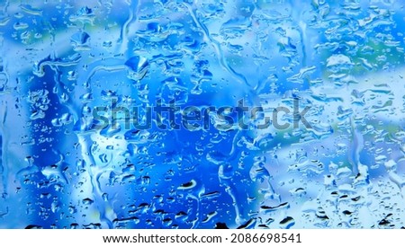 Water drops on glass blue background in winter