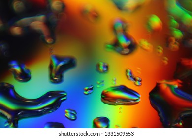 Water drops on mirror with light interference effect, color diffraction. Iridescent blurred holographic surface.