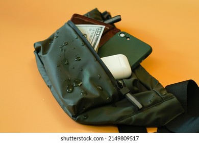 Water drops on a waterproof waist bag on an orange background.  Items. Things. Strap. Style. Textile. Waist. Wallet. Water. Money. New. Object. One. Orange. Packing. Rain. Safe