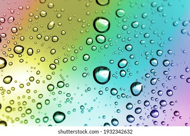Wasser fällt nach dem Regen auf ein Fensterglas. Naturhintergrund in Regenbogenfarbe.