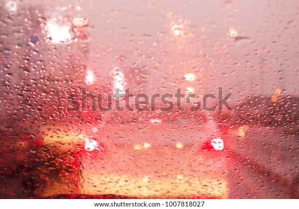 Water drops on the windshield in the
evening city and traffic jam on red tone
background