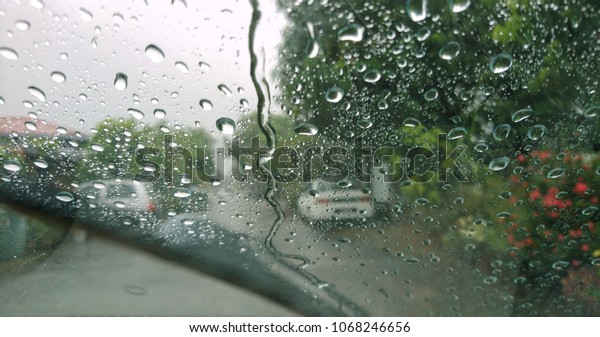 Water drops or rain in\
front of mirror of car on road or street. Driving in rain. Blurred\
background. 