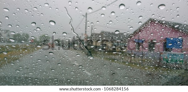 Water drops or rain in\
front of mirror of car on road or street. Driving in rain. Blurred\
background. 