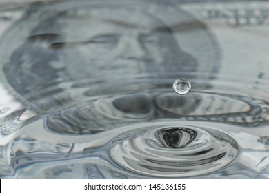 water drops and ripples with a one hundred dollar bill as a background and reflection