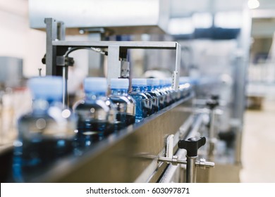 Water factory - Water bottling line for processing and bottling pure mineral water into blue bottles. Selective focus. - Powered by Shutterstock