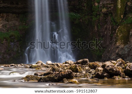 Water falling from a tall cascade along the Ingleton waterfalls trail in North Yorkshire - captured as a long exposure with a ten stop ND filter.