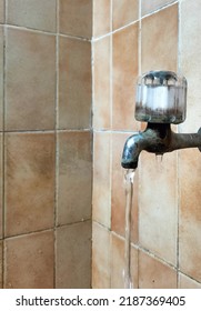 The Water Faucet Gives Off Old Water, With A Brown Porcelain Wall Background