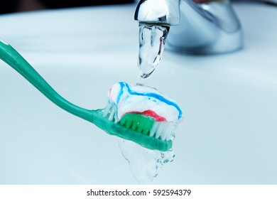 Water from a faucet runs over a toothbrush and toothpaste - Powered by Shutterstock