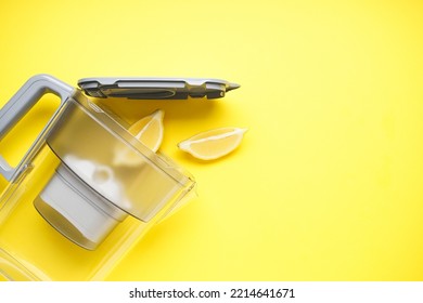 Water Filter Jug With Lemon On A Yellow Background. Top View.