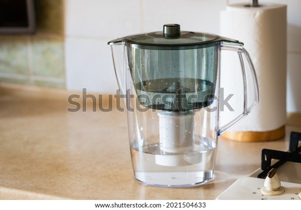 Water filter jug on kitchen table. Clean water\
concept. Filtration\
water.