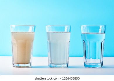 Water filters. Concept of three glasses on a white blue background. Household filtration system.