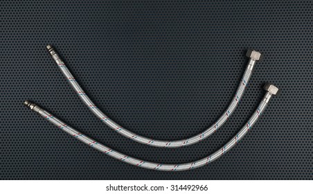 Water flexible hose in metallic braiding on a dark background