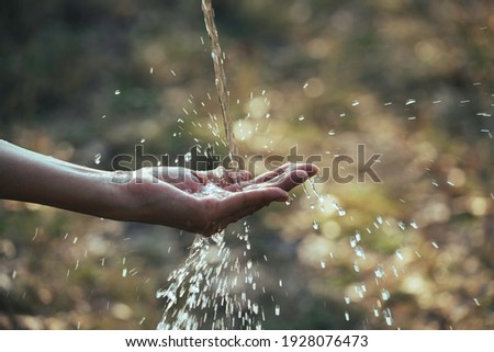 Water flow to hand in the garden on nature background.