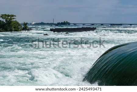 Water flow near hydraulic structures in a lake near Niagara Falls, old barge and bridge in the background, Niagara State Park, USA