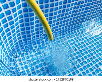 Water Flowing From The Hose Into The Pool Filling. Selective Focus