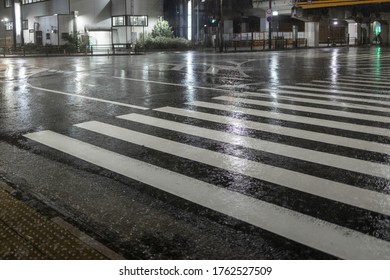 Water flows across crosswalk on empty street at night - Powered by Shutterstock