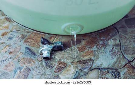 Water Flows From A White Plastic Bucket With A Broken Faucet.